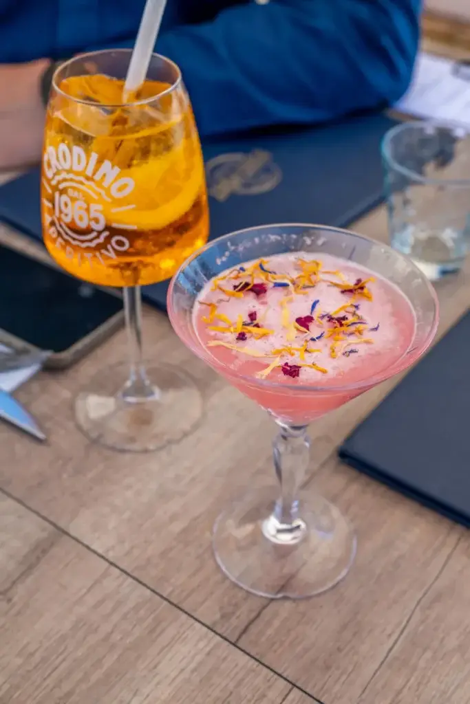 Cocktail rose aux pétales de fleurs posé sur la carte de Chez Pont-Pont