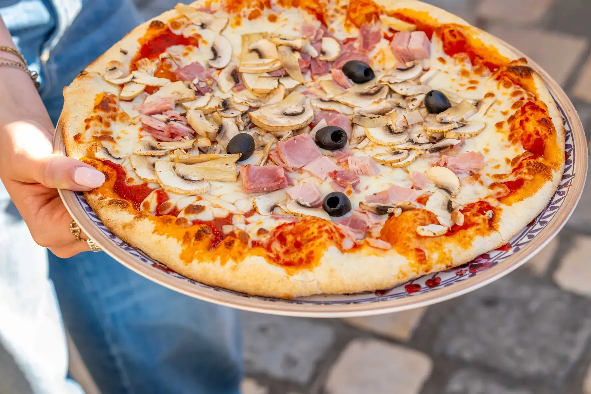 Pizza au jambon, champignons et olives portée à la main, restaurant Chez Pont-Pont