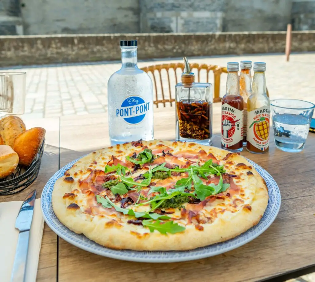 Pizza et bouteille sur la terrasse de Chez Pont-Pont avec vue sur le château