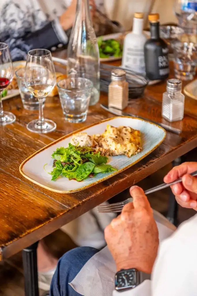Plat du jour avec salade verte et gratin servi à table au restaurant Chez Pont-Pont