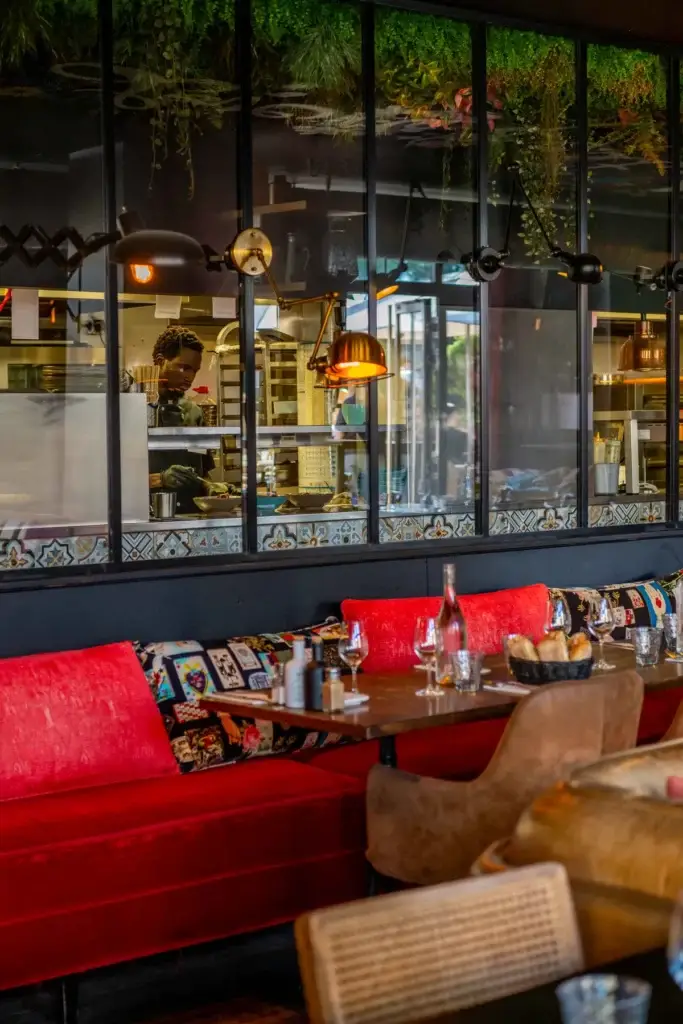 Salle du restaurant Chez Pont-Pont avec banquette rouge et verrière sur la cuisine