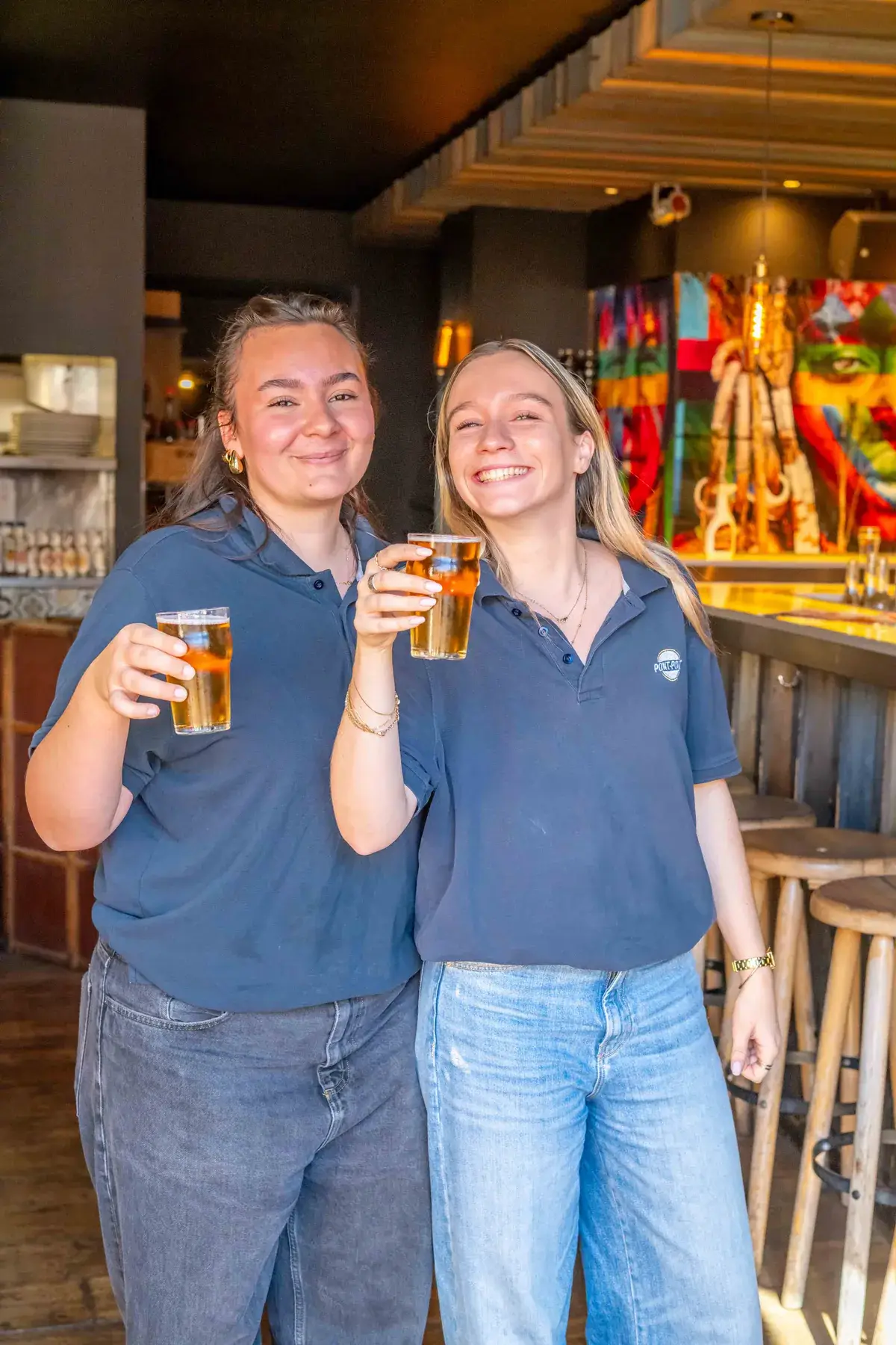 Deux serveuses souriantes tenant une bière au bar de Chez Pont-Pont