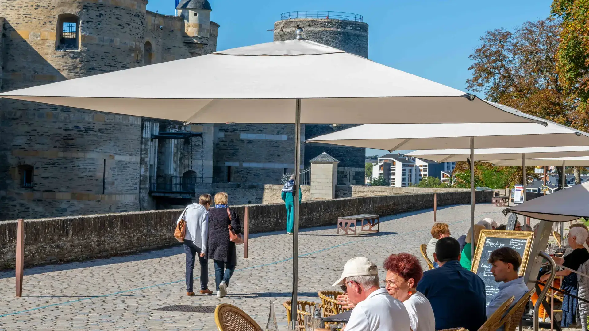 Vue d’ensemble de la terrasse de Chez Pont-Pont avec parasols et château d’Angers