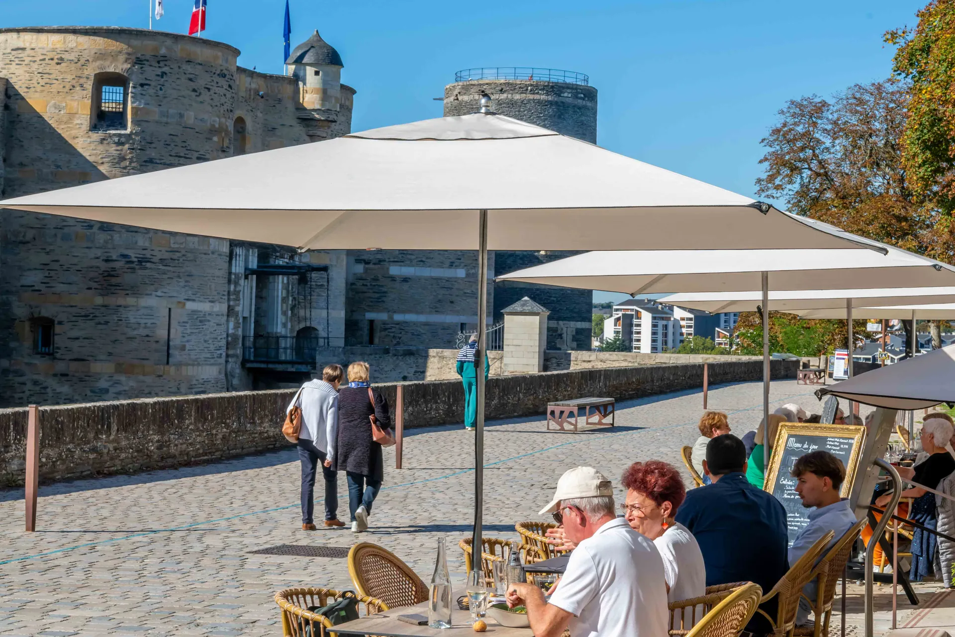 Vue d’ensemble de la terrasse de Chez Pont-Pont avec parasols et château d’Angers